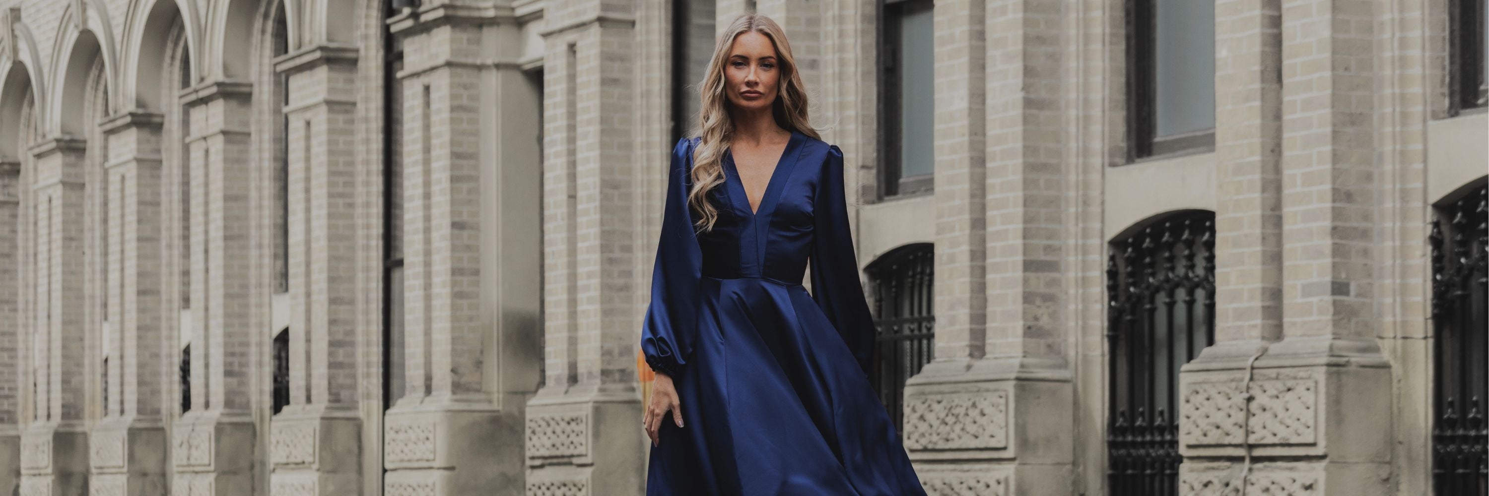 Statement evening maxi dress in navy satin by Rhoen, showcasing puff sleeves, fluid skirt, and daring thigh slit