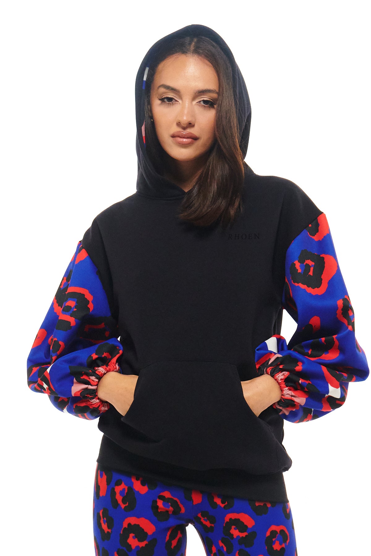 Luxury women’s hoodie with bold cobalt blue and red leopard print sleeves, part of Rebecca Rhoades’ RHOEN collection.