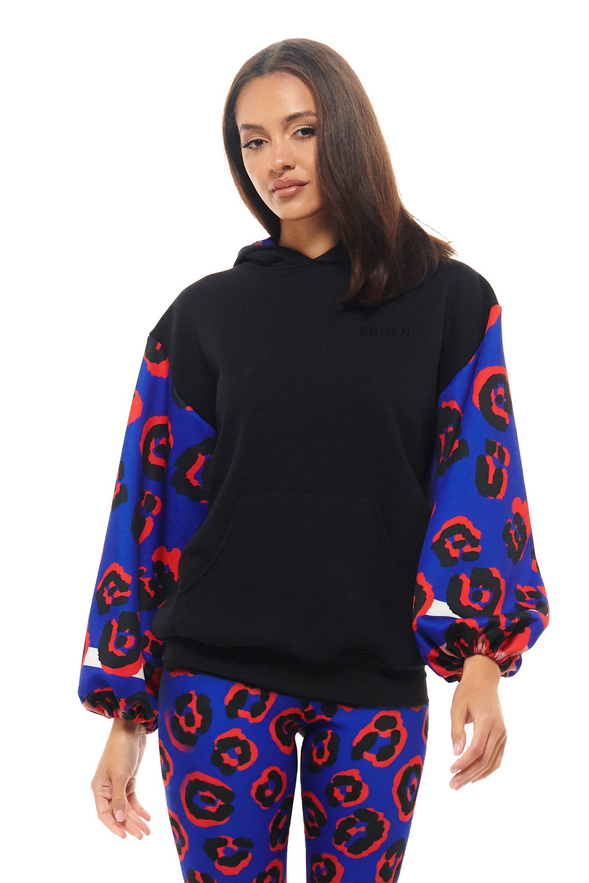 Black RHOEN hoodie with vibrant blue and red abstract leopard print sleeves, styled with matching leggings.