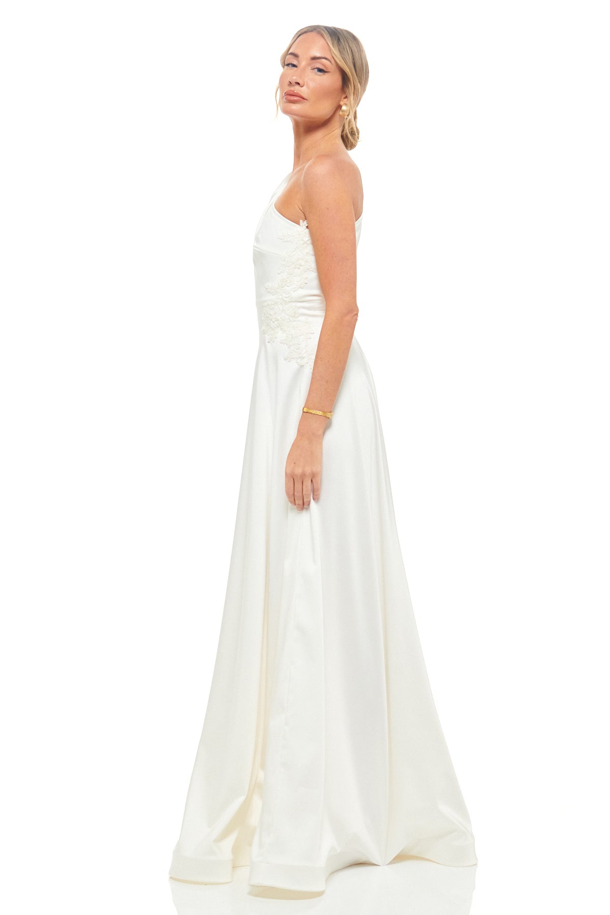 Ivory satin bridal gown by RHOEN – sophisticated one-shoulder maxi dress with flowing skirt and lace embellishment, timeless designer style.