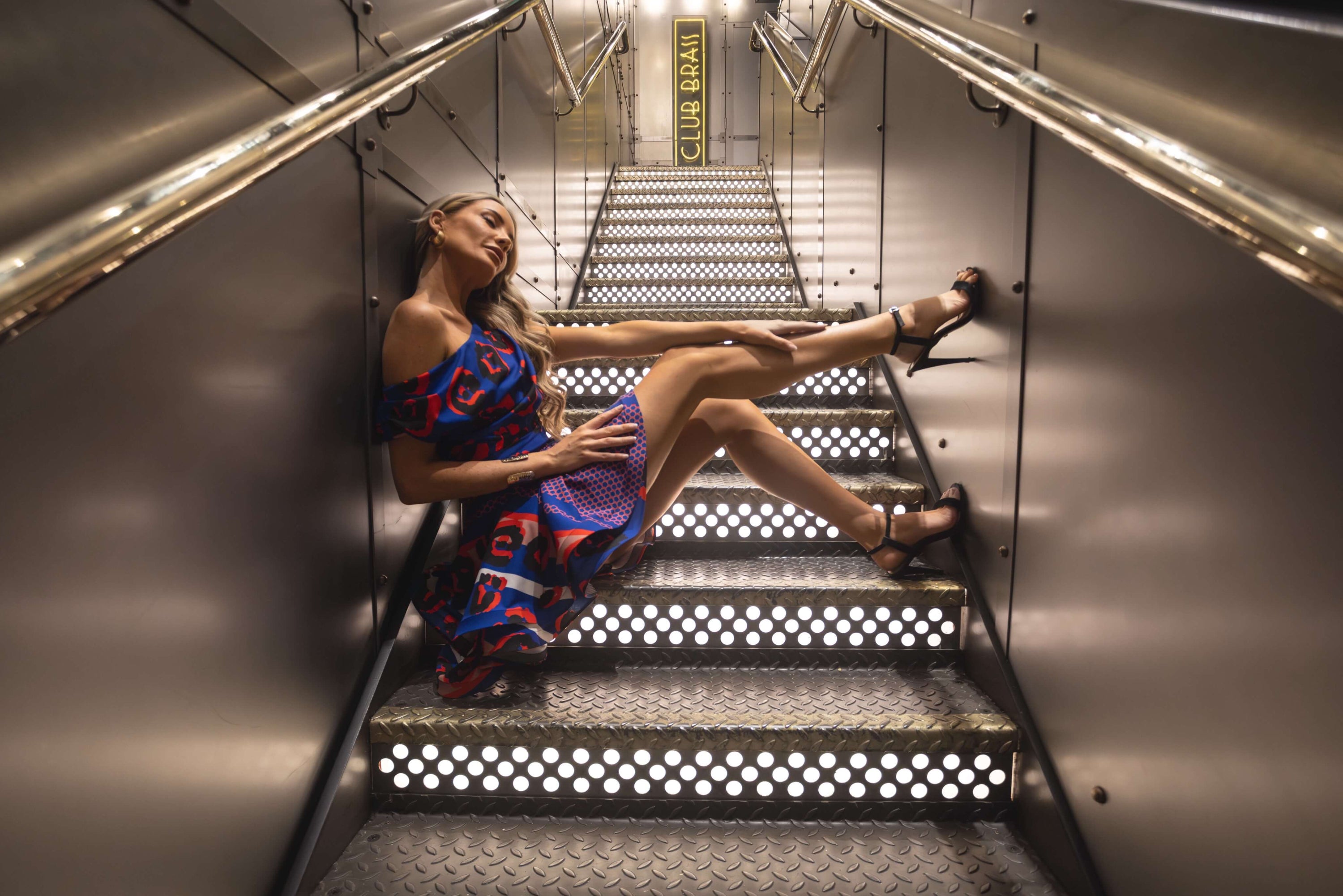 Rhoen signature statement dress in abstract blue and red pattern, styled with strappy black heels at Club Brass.”